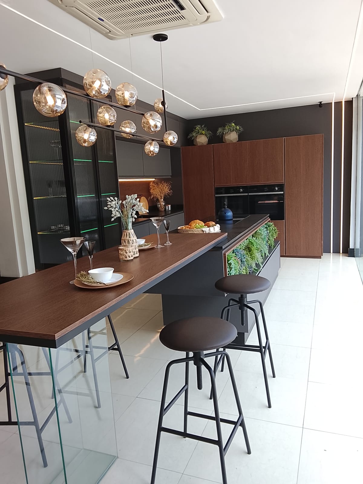 Cozinha planejada com ilha, madeira e iluminação contemporânea